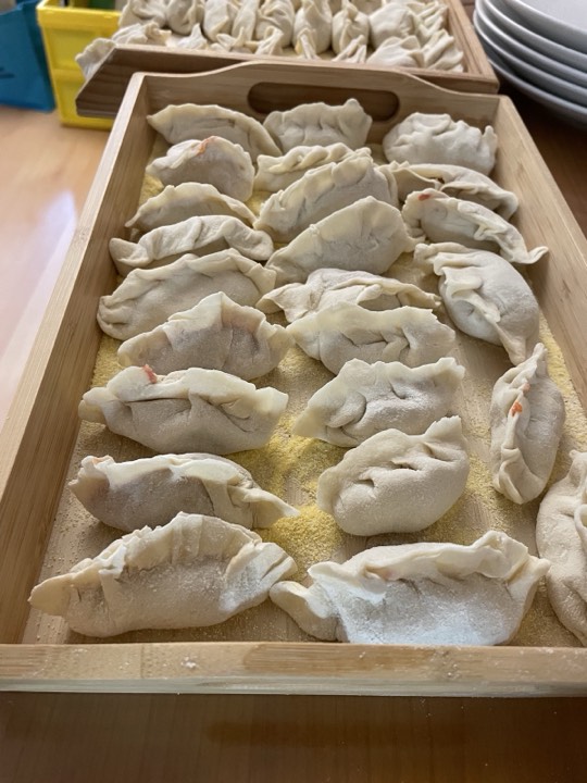 撒了粉的竹盘上排列著刚包好的饺子