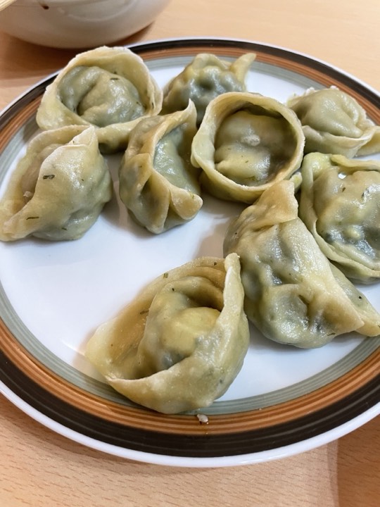 盘中盛著绿色蔬菜馅的饺子